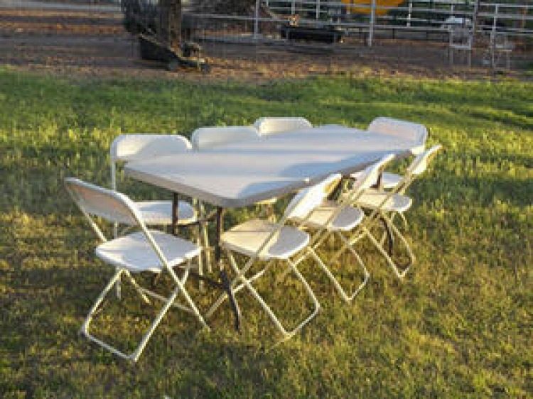 Folding table and white chairs on grass